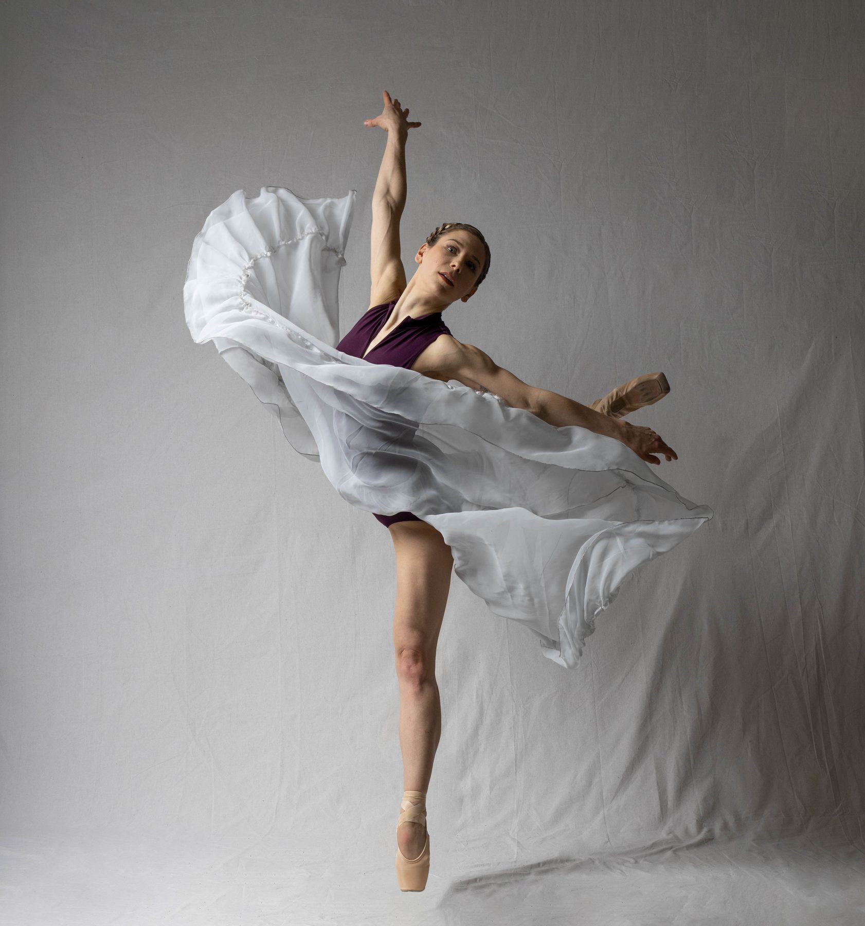 Melissa Panetta balanced on pointe, one arm lifted, skirt caught mid-motion.