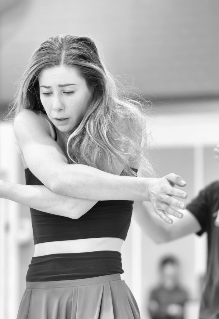 Melissa Panetta mid-phrase in rehearsal, arms crossed in front of her.